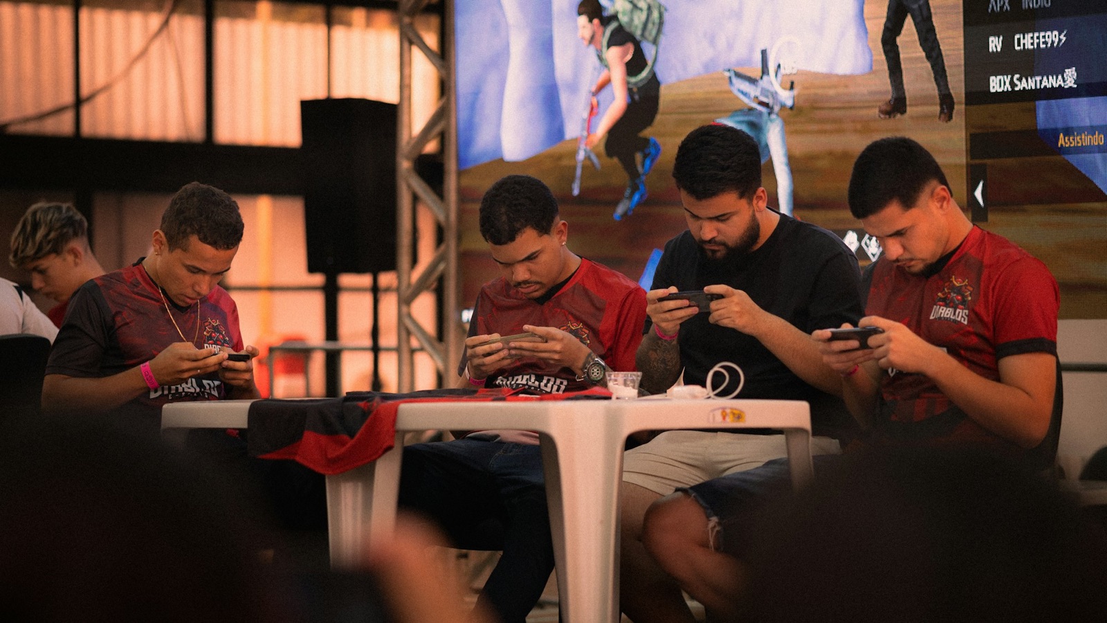 Quatre joueurs sur téléphone pendant un tournoi de jeu mobile sur scène